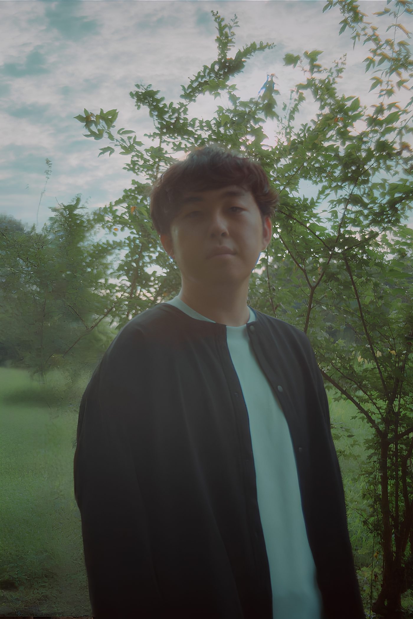 緑の木々を背にした大村優介のポートレート